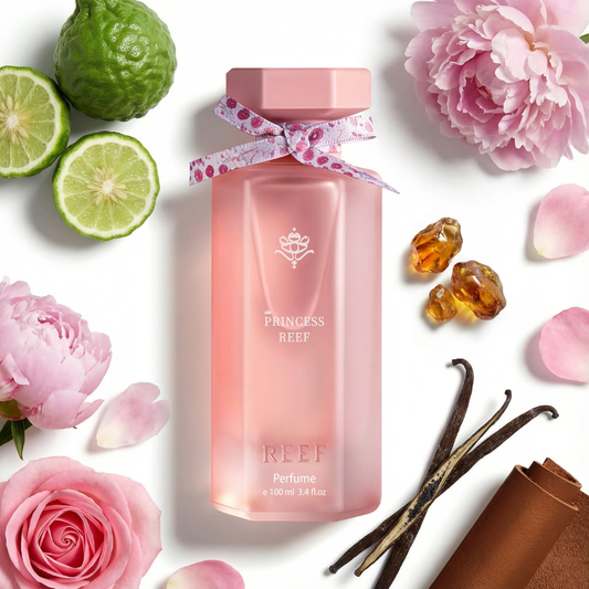 Pink bottle labeled 'Princess Reef' surrounded by flowers, limes, and vanilla beans on a white background