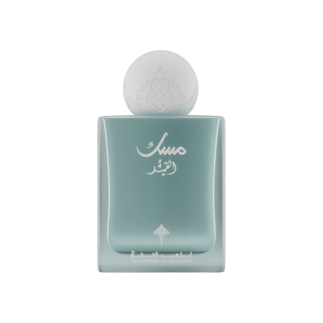 A square glass perfume bottle with a rounded, frosted pale aqua body and a spherical frosted cap, featuring white Arabic script on the front.