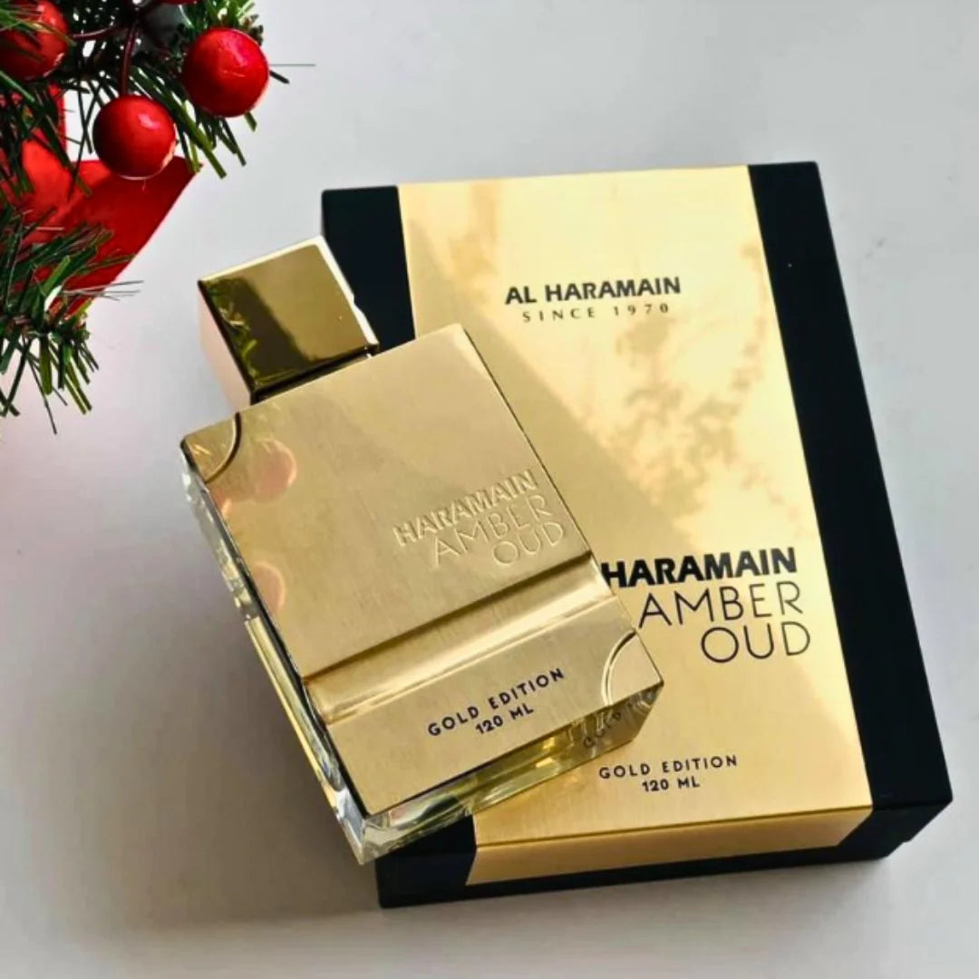 Gold Al Haramain Amber Oud perfume bottle and packaging on a light background with Christmas decorations.
