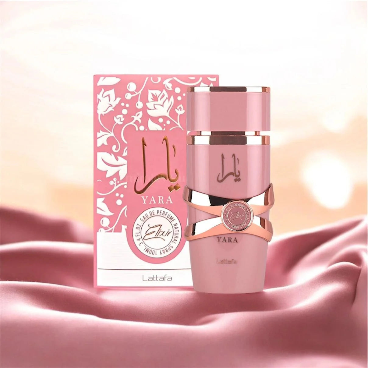 Pink Lattafa Yara perfume bottle and packaging on a pink fabric background